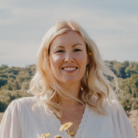 Hayley Allam, co-founder of BellaPause, smiling in a field of wildflowers.